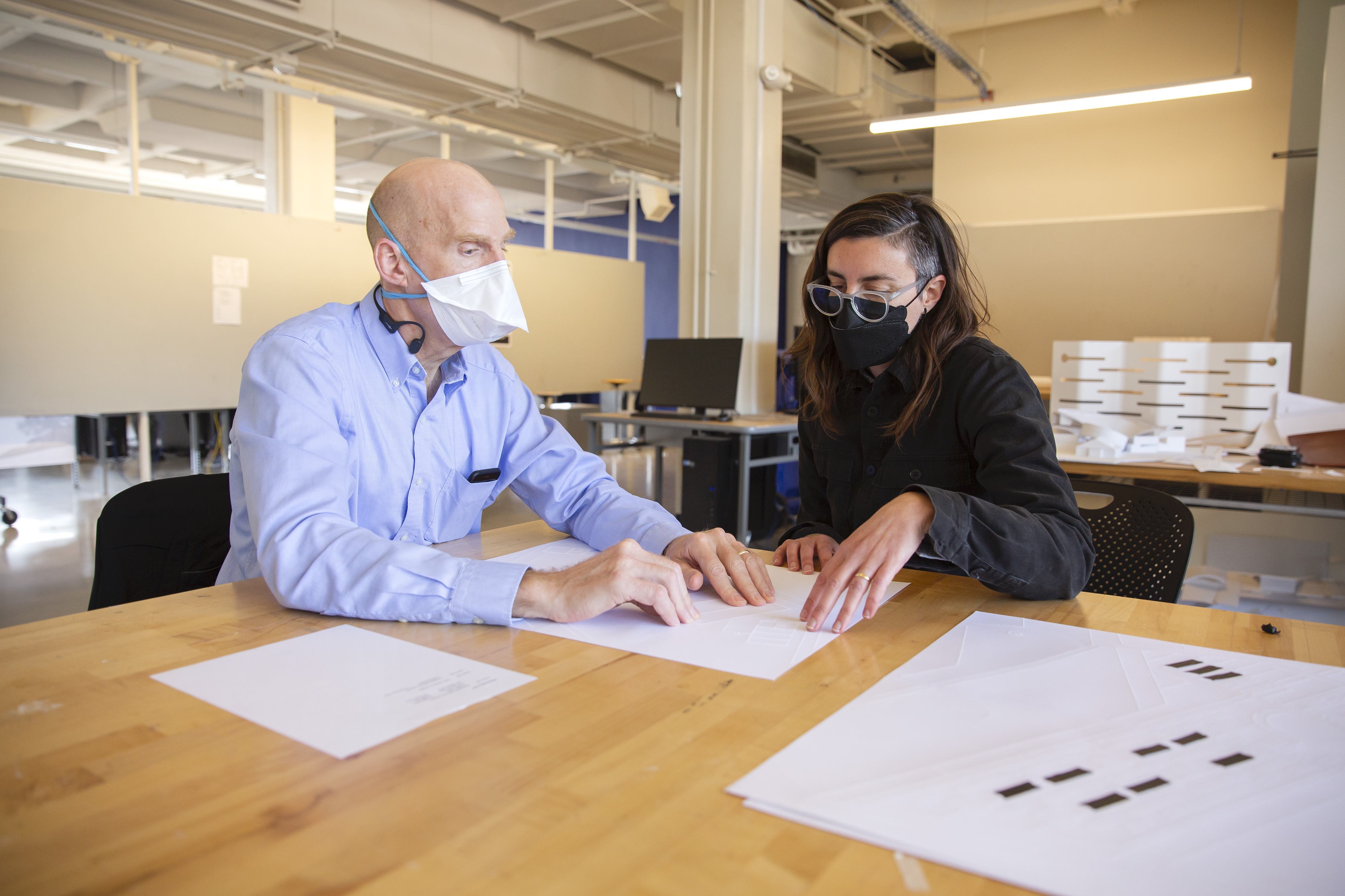 chris downey and a student use their fingers to review plans