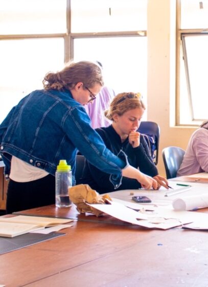 Two students study a drawing in studio