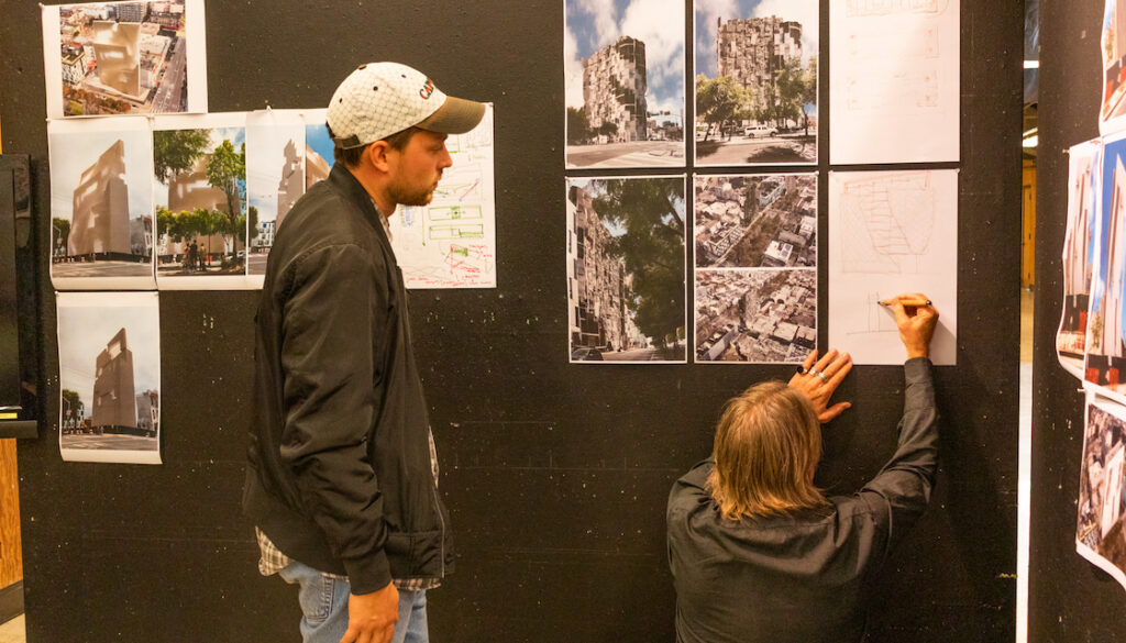 A student watches on as another student adds to their design