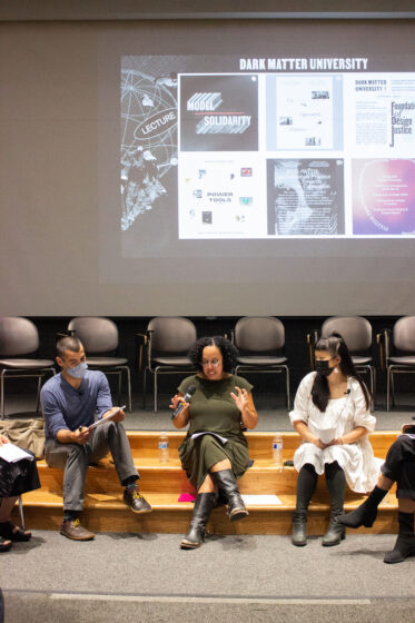 Members of DMU sit on Bauer Wurster Auditorium stage giving their lecture