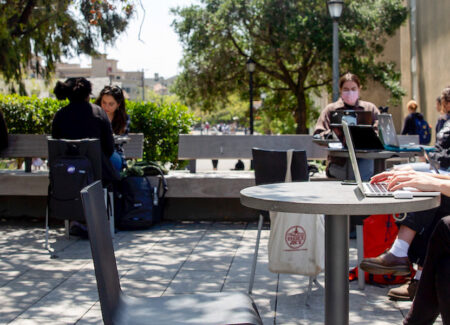 Individual working on their computer in Bauer Wurster courtyard