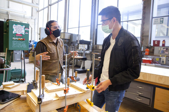 students talking while working on a project in the fabrication shop