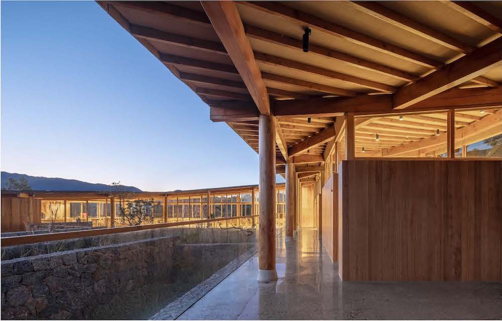 View of a building surrounding a courtyard with exposed wooden pillars and roof.