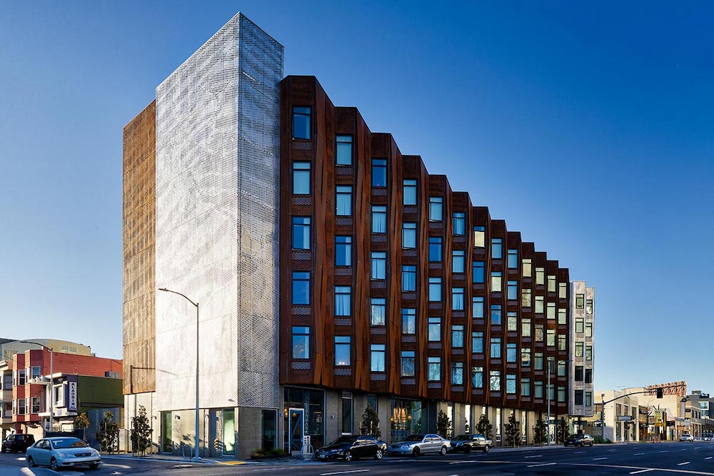 A six-story building, one block long, with a three-dimensional, accordion-lie facade made of rust-colored metal.