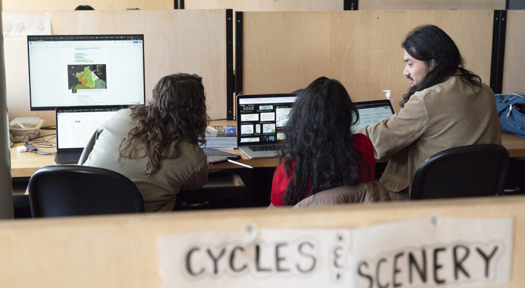 a group of people sitting at a table with computers