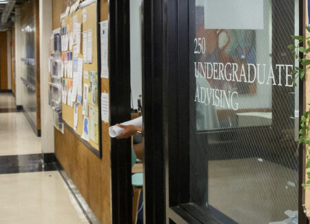 Undergraduate architecture student with hands full of project papers emerging from the CED Undergraduate Advising office