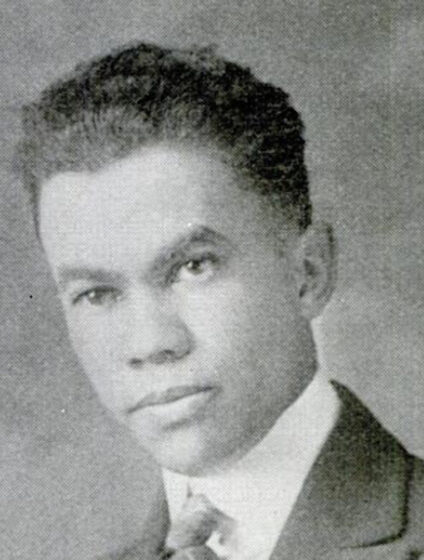 Old formal black-and-white photograph of a young African American man wearing a coat and tie.