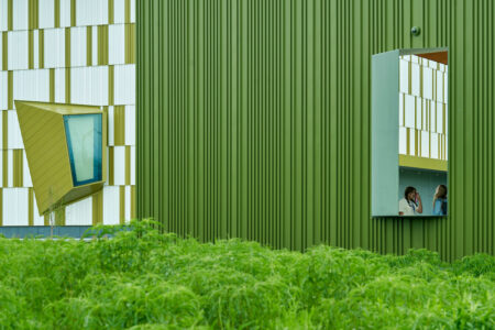 Facade of green building with green vegetation in foreground