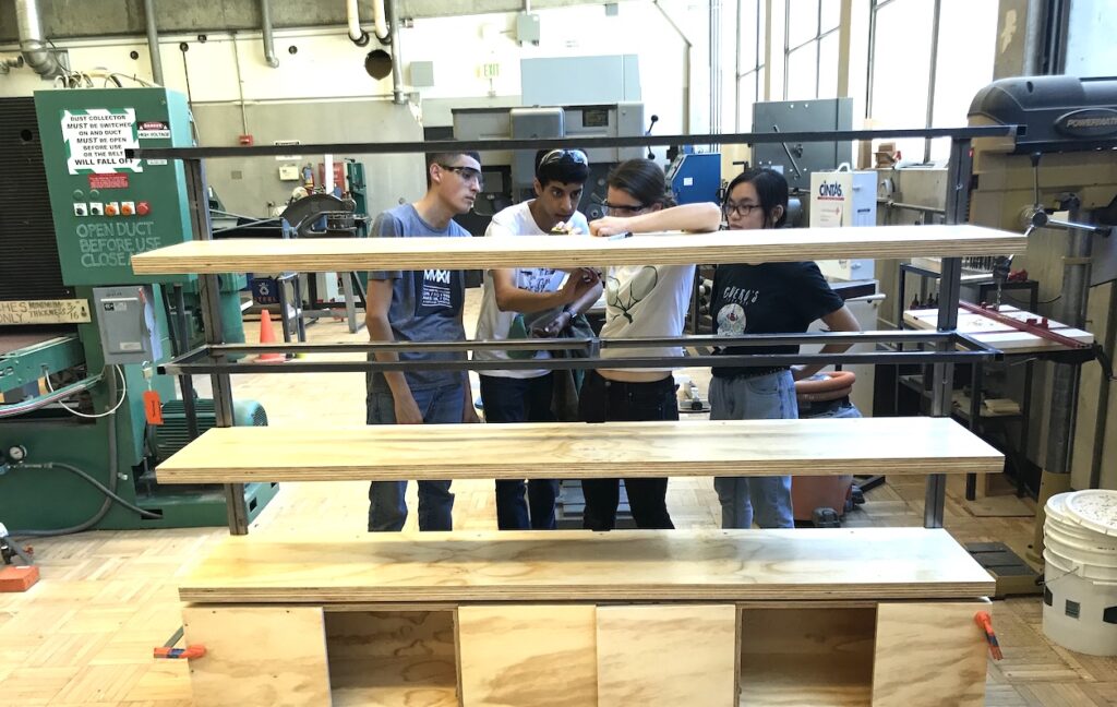 Four teens assembling a wooden structure