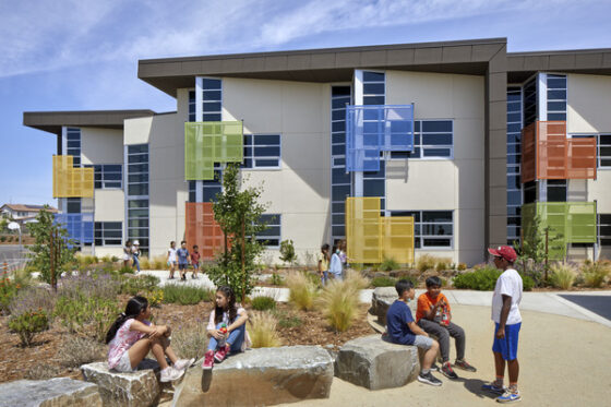 A building with colorful panels with elementary-school-age children in front