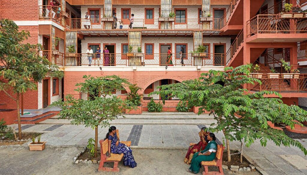 Housing complex India overlooking courtyard where women sit