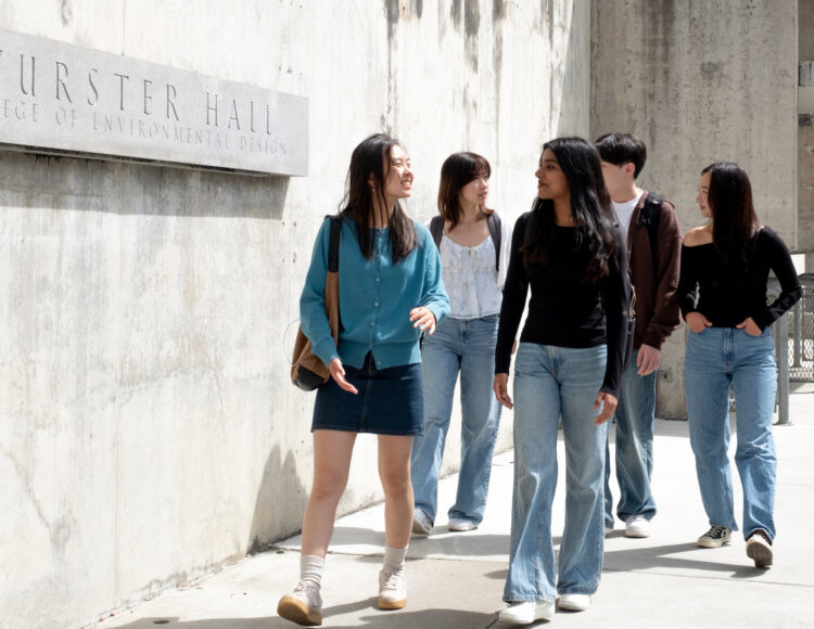 Group of students walking next to concrete wall with sign saying Wurster Hall College of Environmental Design