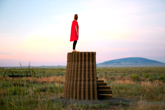 Woman in red dress standing on mud wall in landscape