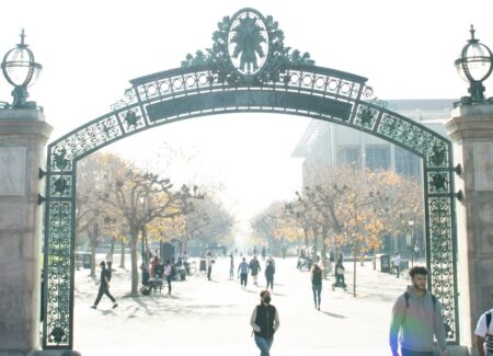 a group of people walking on path in front of Sather Gate