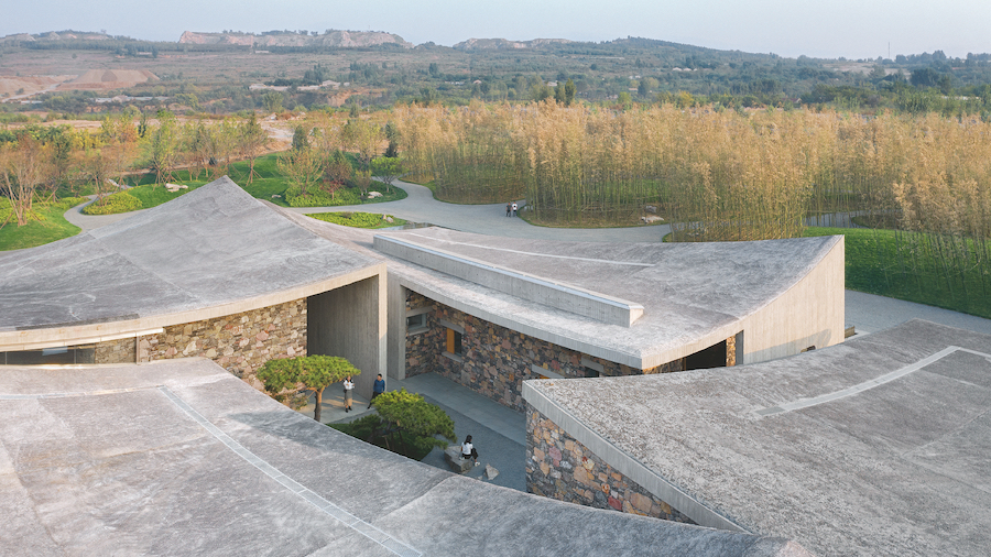 cluster of buildings with heavy concrete roofs with field in background