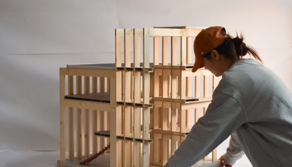 student in grey sweater placing wood model on table