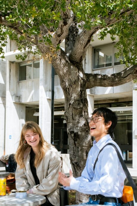 a man and woman sitting at a table under a tree