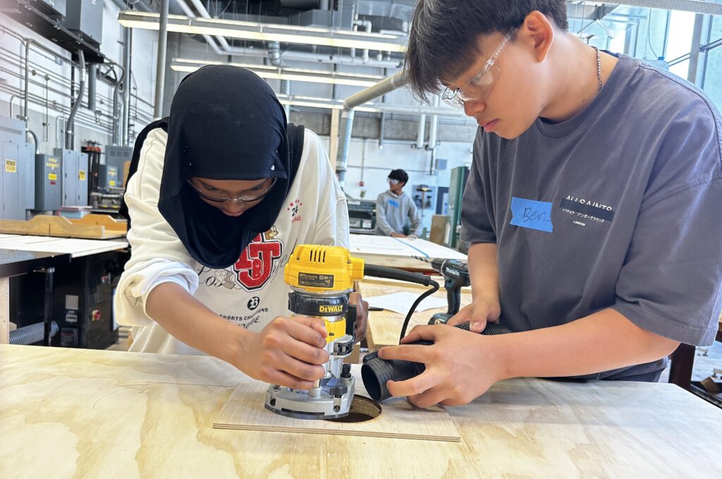 two teen students working with power tool