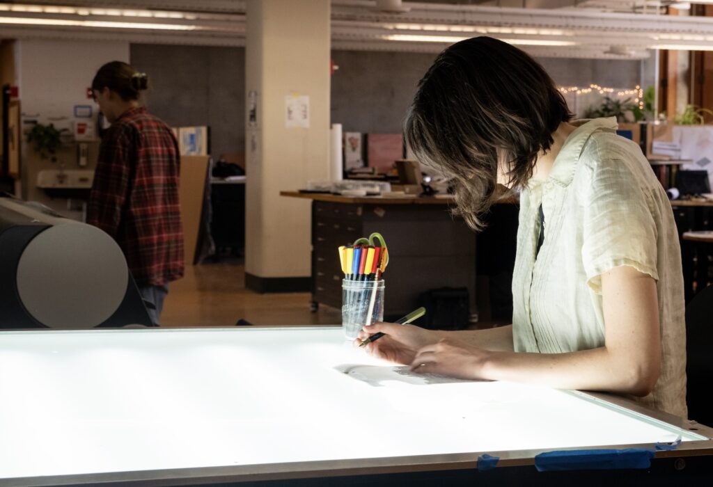 woman writing on a paper on lightbox