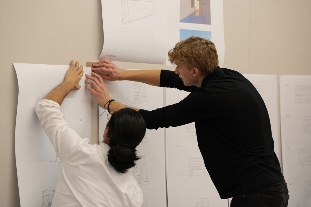 Two graduate architecture students using ruler at pin up