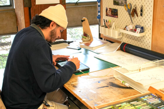 Student in hat drawing on tablet