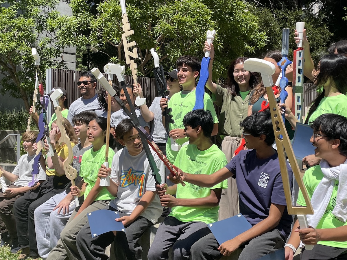 group of young students holding self-made mini clubs in the air