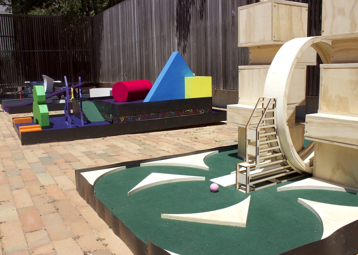 two mini golf holes on display on brick pavement