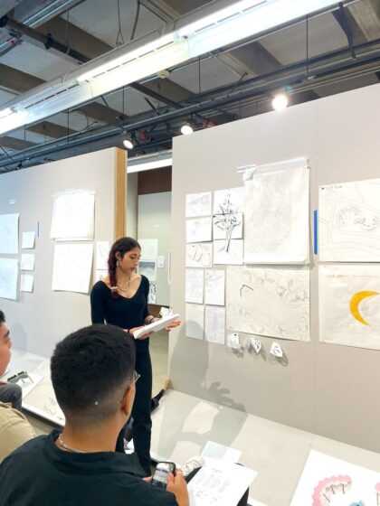 A student standing giving a review of her work in the program.